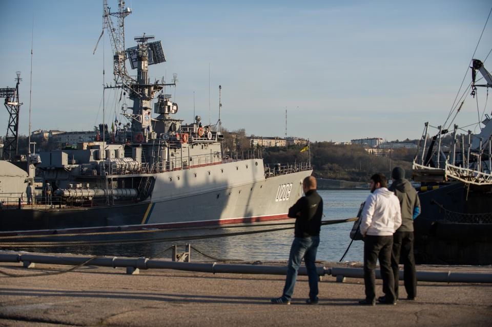 People look at Ukrainian navy ship Slavutich at harbor of Sevastopol, Ukraine, Monday, March 3, 2014. The Ukrainian Defense Ministry said that Russian forces that have overtaken Ukraine's strategic region of Crimea are demanding that the ship's crew surrender. (AP Photo/Andrew Lubimov)