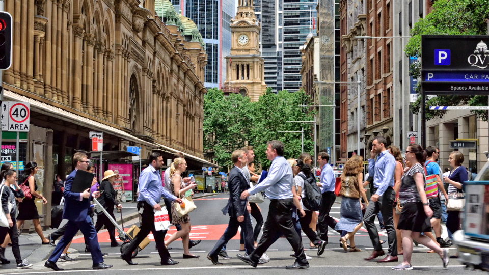 Office workers cross a busy street in the Sydney CBD