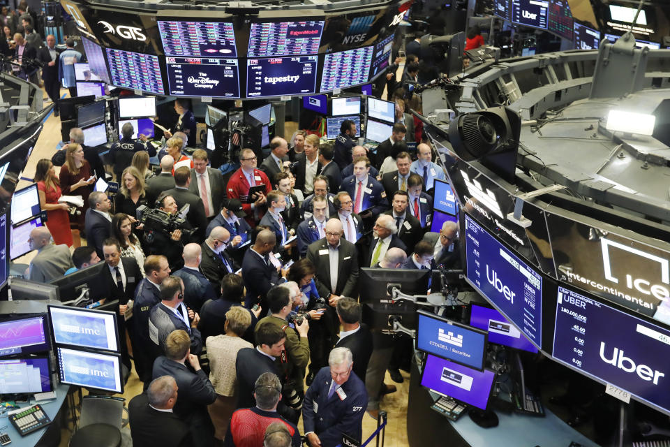 Stock traders gather around the post where Uber shares will begin trading during the company's initial public offering at the New York Stock Exchange, Friday, May 10, 2019. (AP Photo/Richard Drew)