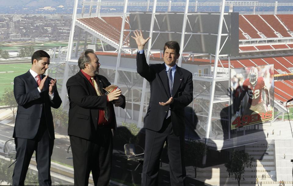 San Francisco 49ers head coach Jim Harbaugh, right, waves as he stands next to team owner Jed York, left, and Santa Clara Mayor Jamie Matthews at a groundbreaking ceremony at the construction site for the 49ers' new NFL football stadium in Santa Clara, Calif., Thursday, April 19, 2012. (AP Photo/Jeff Chiu)