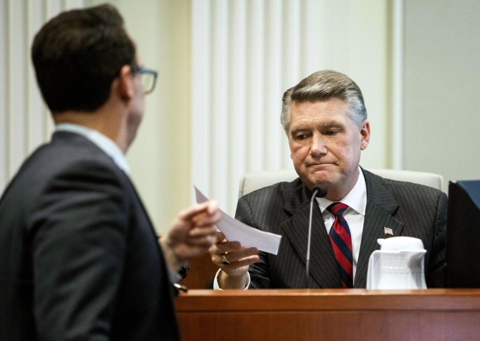 Josh Lawson, chief counsel for the state Board of Elections and Ethics Enforcement, left, hands Mark Harris, Republican candidate in North Carolina's 9th congressional race, a document during the fourth day of a public evidentiary hearing on the 9th congressional district voting irregularities investigation Thursday, Feb. 21, 2019, at the North Carolina State Bar in Raleigh, N.C. (Travis Long/The News & Observer via AP, Pool)