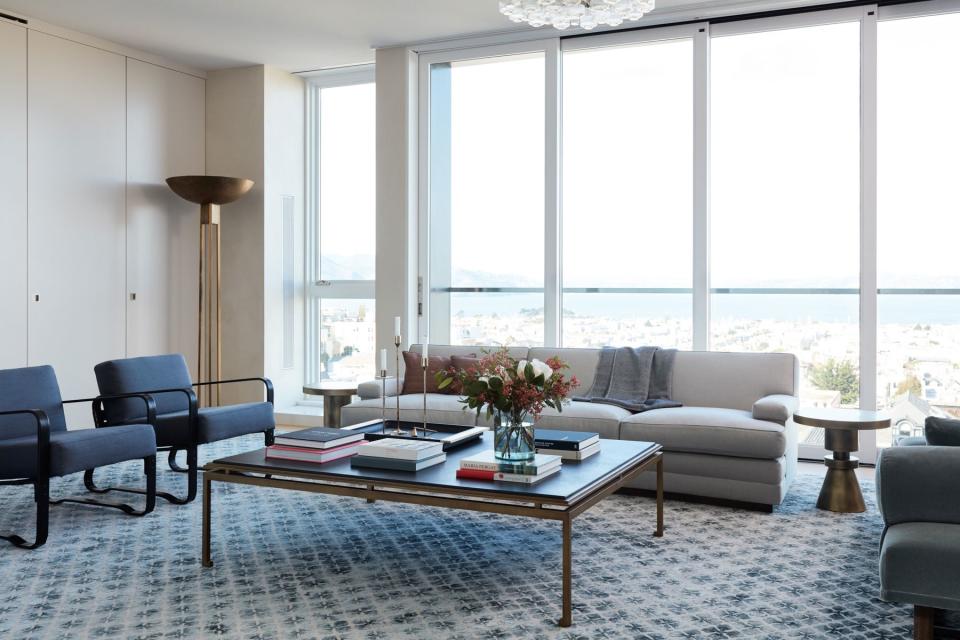 The bay's natural jewel tones informed the palette for this sitting room, a favorite spot for cocktails when the couple entertains. A Holland & Sherry rug ties together the cream Habité wool sofa, slate mohair daybed, and pair of rich blue armchairs. “We didn’t want anything to interfere with the view, so we kept things pretty low,” Kwong explains.  A vintage blown-glass chandelier catches the natural light, above.