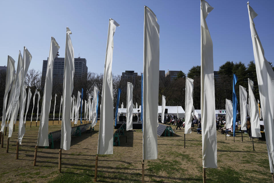 Artists perform on stage surrounded by decorations of "peace flags" to commemorate the 311 disaster following an earthquake and tsunami in the Tohoku region 12 years ago, during an anniversary event at Hibiya Park in Tokyo, Saturday, March 11, 2023. (AP Photo/Hiro Komae)