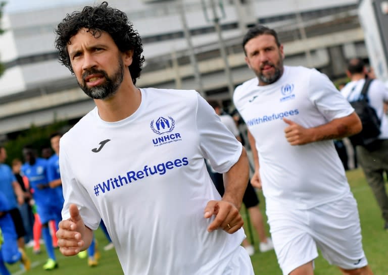 Former Italian footballer Damiano Tommasi leads out ex-French player Vincent Candela to take on the refugee team