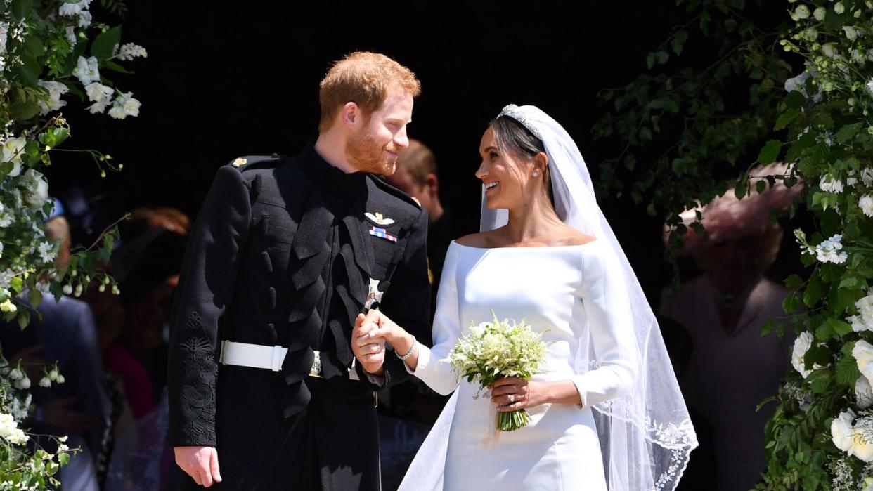 prince harry, in a black military uniform, and meghan markle, in a long sleeved white gown and veil, leave the chapel during their 2018 wedding