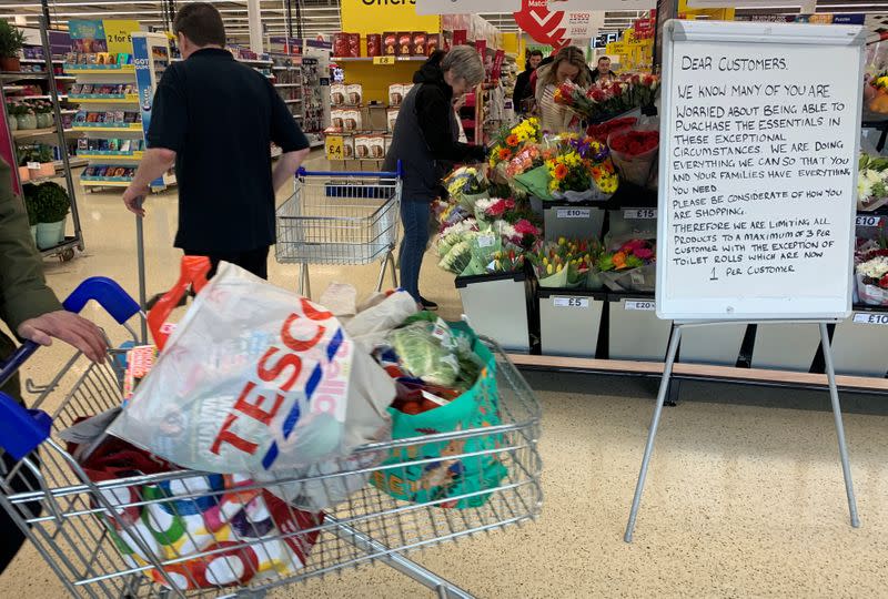 A customer walks past a sign informing shoppers about limited stock inside a Tesco supermarket, during the coronavirus disease (COVID-19) outbreak, in Liverpool