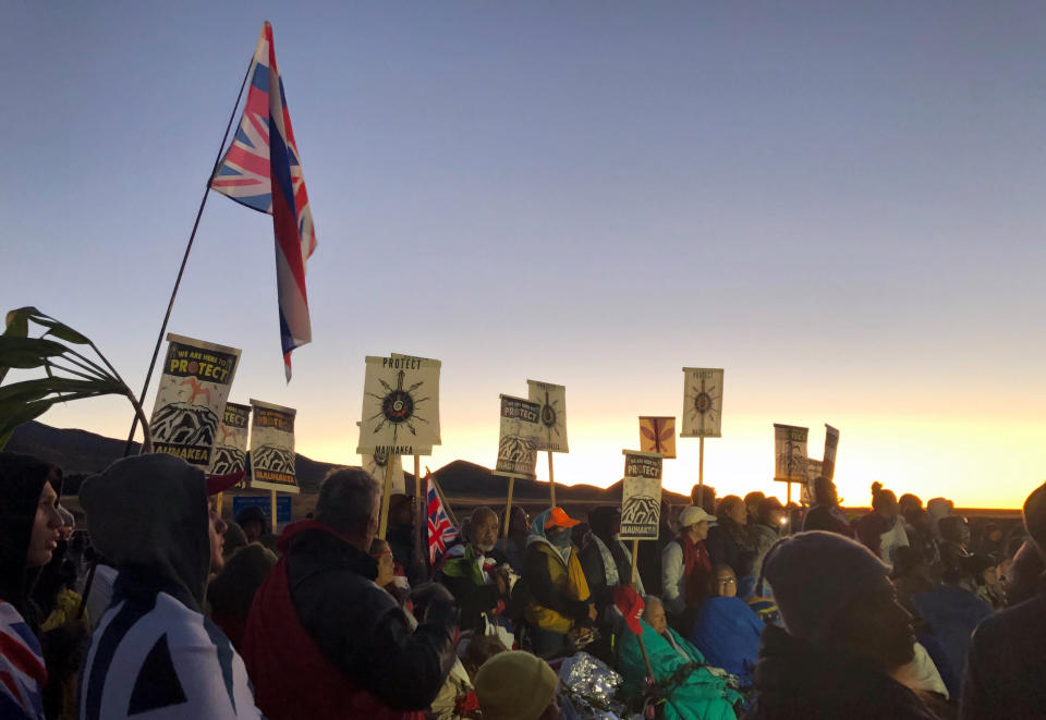 Demonstrators are gather to block a road at the base of Hawaii's tallest mountain, Monday, July 15, 2019, in Mauna Kea, Hawaii, to protest the construction of a giant telescope on land that some Native Hawaiians consider sacred. (AP Photo/Caleb Jones)