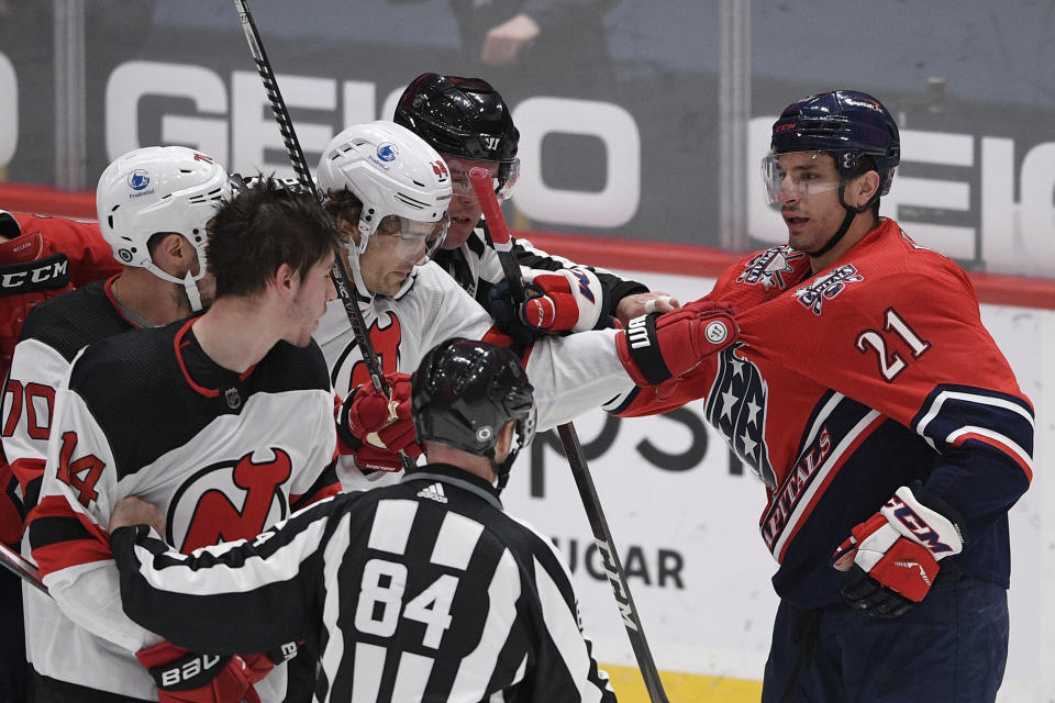 Washington Capitals right wing Garnet Hathaway (21) scuffles with New Jersey Devils left wing Miles Wood (44), defenseman Dmitry Kulikov (70) and right wing Nathan Bastian (14) during the second period of an NHL hockey game Tuesday, March 9, 2021, in Washington. (AP Photo/Nick Wass)