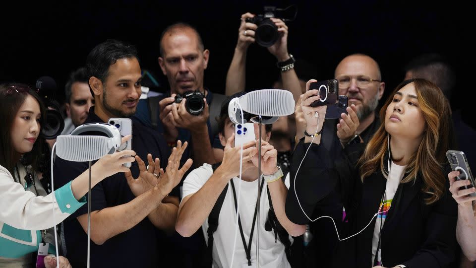 A crowd gathers around the Apple Vision Pro headset as it is displayed in a showroom on the Apple campus in Cupertino on June 5. - Jeff Chiu/AP