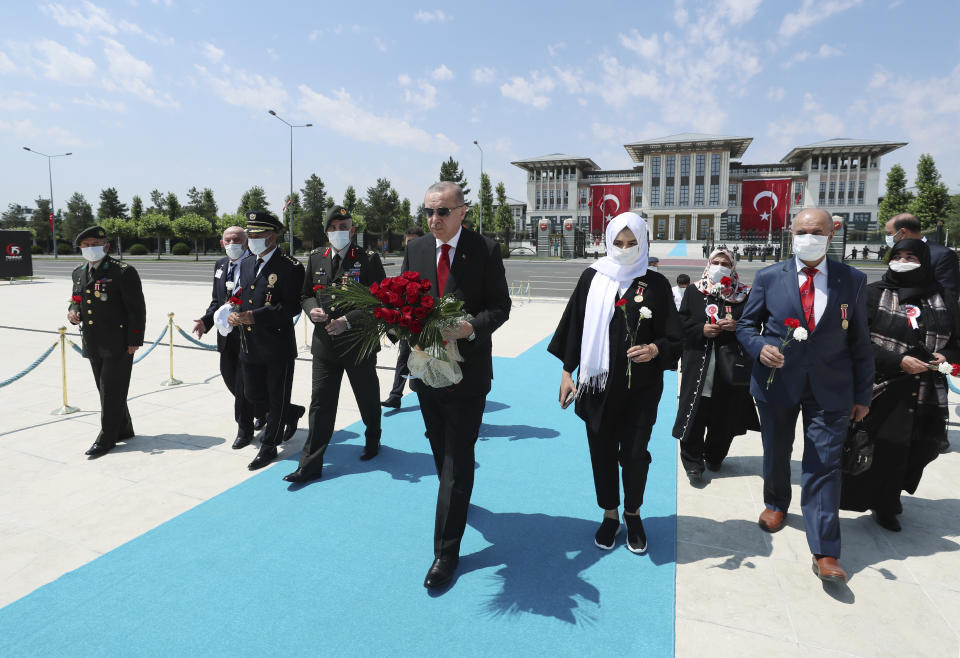 Turkey's President Recep Tayyip Erdogan and family members of coup victims walk to place a floral tribute at the "Martyrs Monument" outside his presidential palace, in Ankara, Turkey, Wednesday, July 15, 2020. Turkey is marking the fourth anniversary of the July 15 failed coup attempt against the government, with prayers and other events remembering its victims. (Turkish Presidency via AP, Pool)