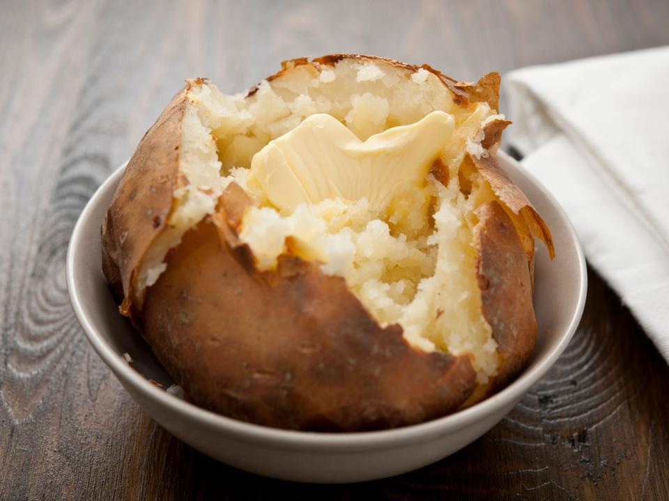 Baked potato in a bowl with butter on top.