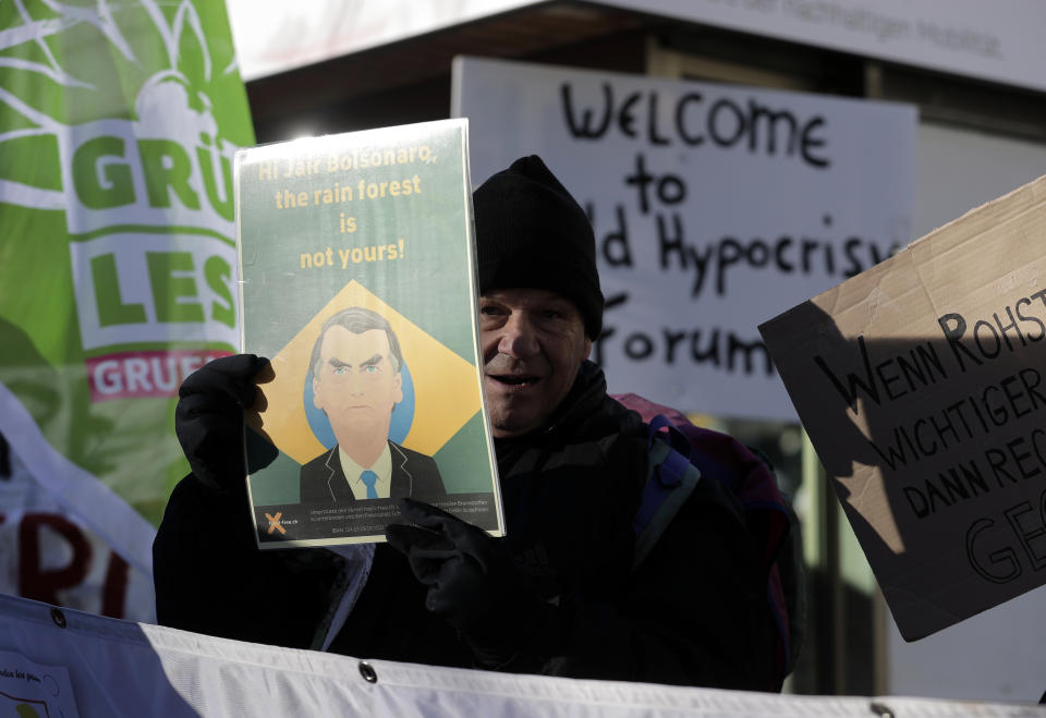 A demonstrator holds up a poster with a picture of Brazilian President Jair Bolsonaro and the words "Hi Jair Bolsonaro, the rain forest is not yours" during a protest outside the annual meeting of the World Economic Forum in Davos, Switzerland, Thursday, Jan. 24, 2019. (AP Photo/Markus Schreiber)
