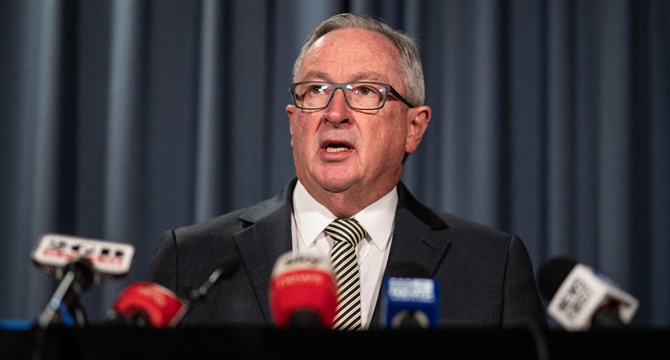 NSW Minister for Health Brad Hazzard stands at a podium to speak to the media during a press conference.