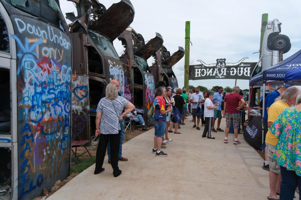 Attendees look over the buried Big Texan limousines Friday at the christening of the new Big Texan Route 66 Bug Ranch in Amarillo.