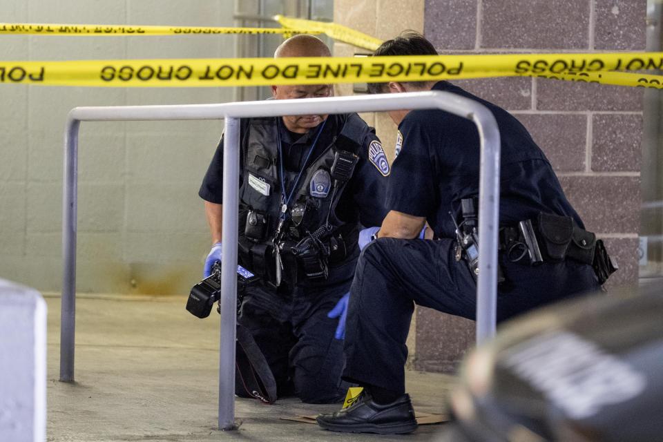 Police officers photograph bullets and a firearm magazine at a crime scene following a shooting at the parking garage for the Fashion Centre at Pentagon City, also known as Pentagon City Mall, Monday, July 1, 2019, in Arlington. (AP Photo/Andrew Harnik)