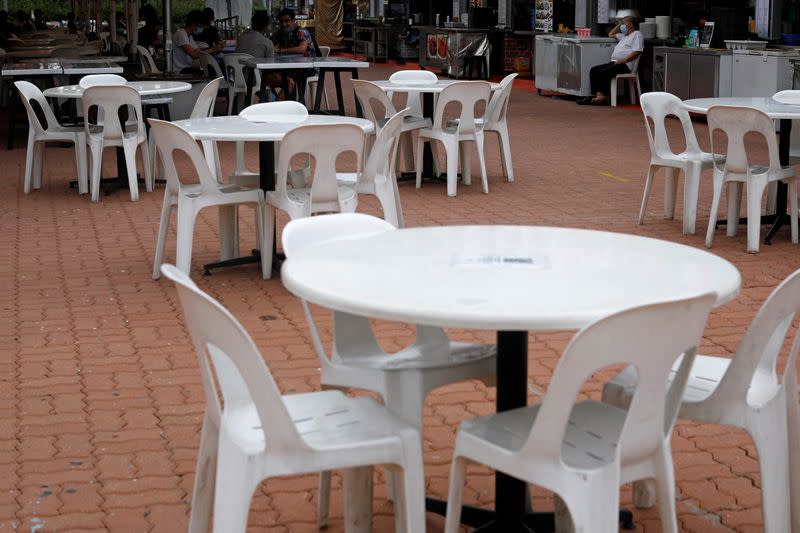 Stall owner waits for customers at a largely empty food court in Singapore