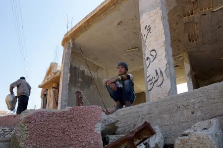 A boy sits at a damaged property in the rebel held al-Ghariyah al-Gharbiyah town, in Deraa province, Syria February 28, 2016. Picture taken February 28, 2016. REUTERS/Alaa Al-Faqir