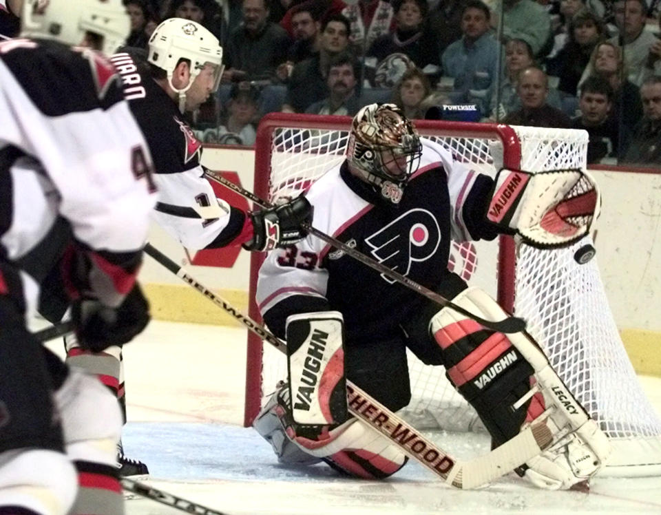 FILE - In this April 16, 2000, file photo, Philadelphia Flyers goalie Brian Boucher makes a save on a shot by Buffalo Sabres left wing Dixon Ward during the second period of an NHL hockey playoff game in Buffalo, N.Y. Boucher had a front-row seat to the five-overtime game between the Tampa Bay Lightning and Columbus Blue Jackets on Tuesday, Aug. 11, 2020. Boucher was working it as the between-the-benches analyst for NBC Sports, 20 years after he played goal in a five-overtime game himself, in May 2000 against the Pittsburgh Penguins. (AP Photo/Don Heupel, File)