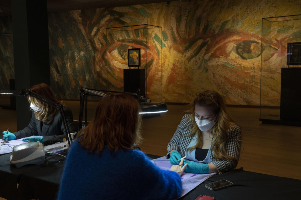 A woman gets a manicure at the Van Gogh museum in Amsterdam, Wednesday, Jan. 19, 2022, as Dutch museums, theaters and concert halls played host Wednesday to businesses that are allowed to open to customers as a protest against their own continuing lockdown closures. (AP Photo/Peter Dejong)