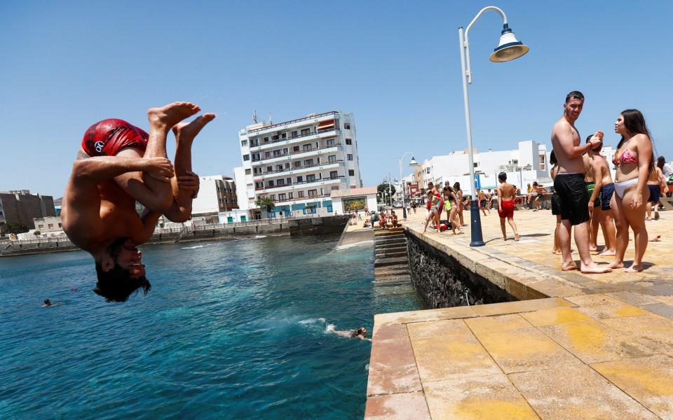 A young man jumps to bathe on Arinaga Beach as some Spanish provinces are allowed to ease lockdown restrictions during phase two, on the island of Gran Canaria - BORJA SUAREZ/ REUTERS