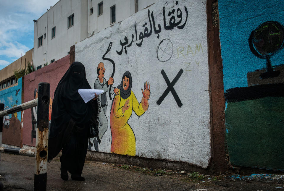 <p>A woman walks by a mural discouraging domestic violence outside if Al-Shifa hospital. According to a 2012 study, some 37% of women are subjected to domestic violence by their husbands. (Photograph by Monique Jaques) </p>