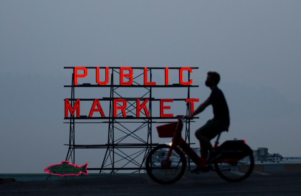SEATTLE, WA - SEPTEMBER 11: Wildfire smoke obscures the view of Elliott Bay as a person bikes past a Pike Place Market sign on September 11, 2020 in Seattle, Washington. According to reports, air quality is expected to worsen as smoke from dozens of wildfires in forests of the Pacific Northwest and along the West Coast descends onto the region. (Photo by Lindsey Wasson/Getty Images)