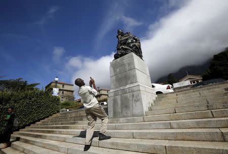 A student takes pictures of a statue of Cecil John Rhodes wrapped in plastic bags as part of a protest at the University of Cape Town March 20, 2015. REUTERS/Mike Hutchings