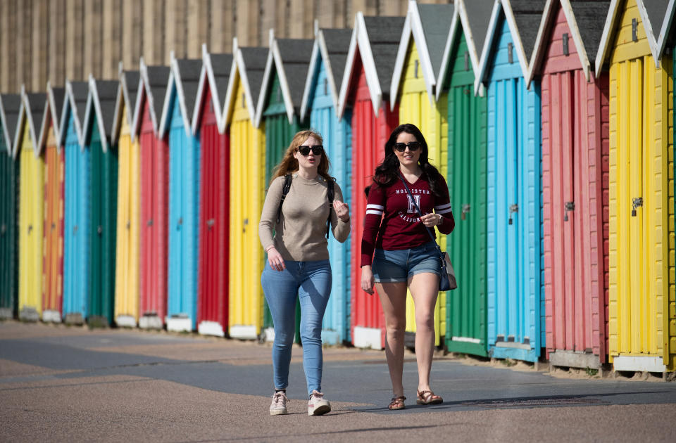 People make their way past beach huts on the sea front on Boscombe beach in Dorset. Picture date: Tuesday March 30, 2021. Temperatures in parts of the UK are expected to be significantly warmer this week as families and friends are reunited and sporting activities are allowed to resume in England.