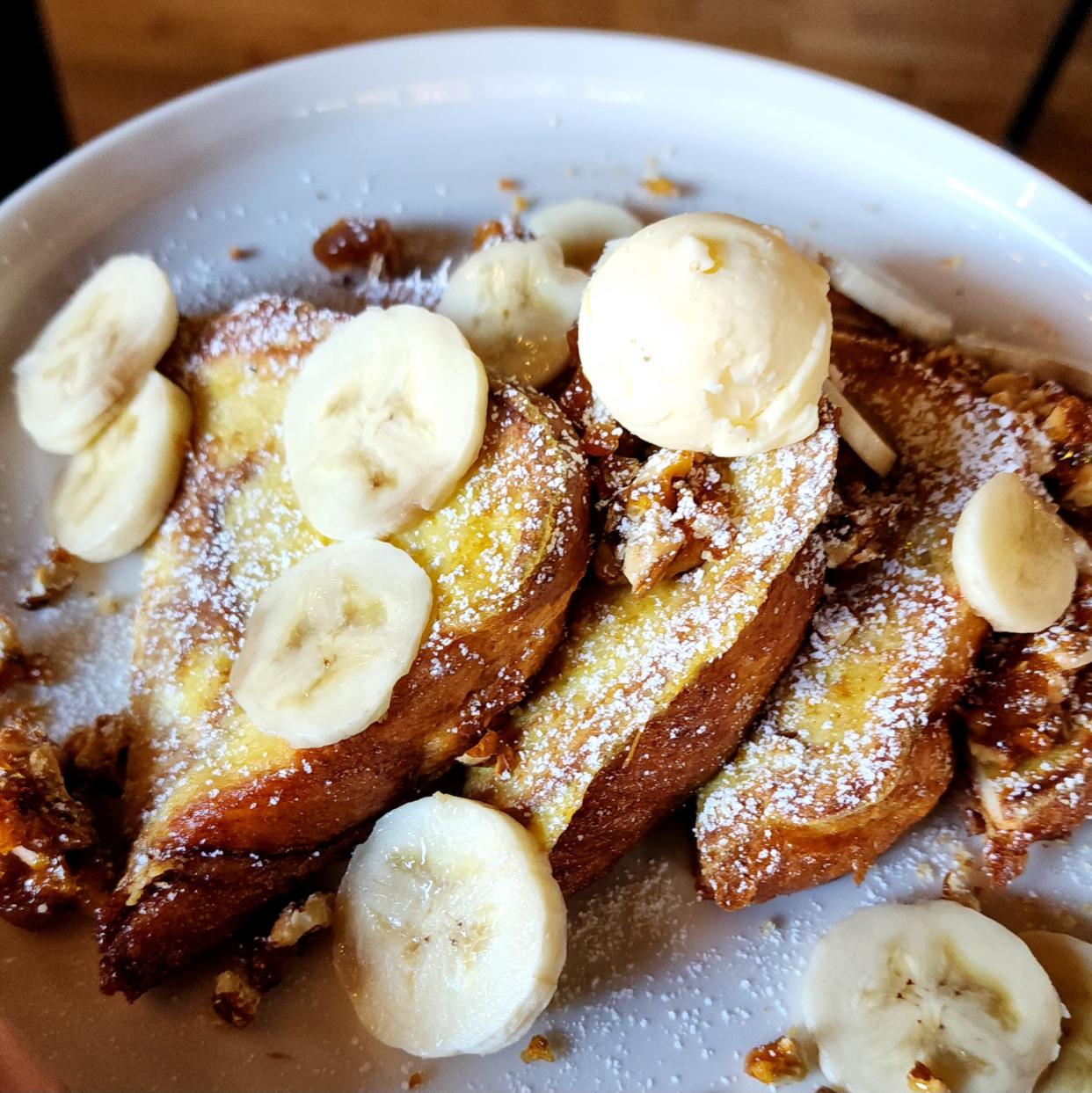French Toast at The Patio on Broadway comes with fresh banana and candied walnuts on cinnamon bread and is served with maple syrup.