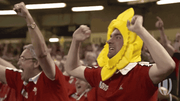 Person in a banana costume at a sporting event, cheering enthusiastically with others