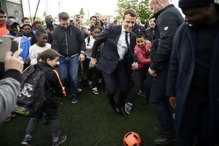 Emmanuel Macron (C), head of the political movement En Marche !, or Onwards !, and candidate for the 2017 presidential election, kicks a soccer ball during a campaign visit in Sarcelles, near Paris, April 27, 2017. REUTERS/Martin Bureau/Pool