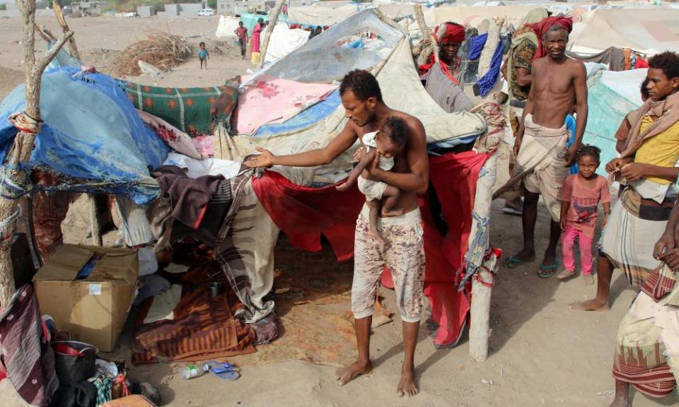 People displaced by the war in Yemen’s west coast areas gather outside their tent at a camp near Aden, Yemen, on 27 May 27.