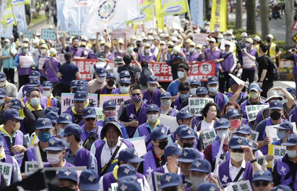 FILE - Taiwanese workers hold signs reading "Flunking governing. Labor ledger," as they protest on the street to ask for increasing labor welfare during a May Day rally in Taipei, Taiwan, Monday, May 1, 2023. The term 山道猴子 (shan dao hou zi), "mountain roadmonkey," became popular shorthand for young people's economic pressures in August, when a YouTube user dropped a 20-minute film called the "Life of a Mountain Roadmonkey." His story touched off a discussion about the low wages and long hours for many in Taiwan, where housing and traditional "success" are often out of reach. (AP Photo/Chiang Ying-ying, File)