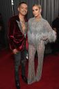 <p>In a glitzy see-through jumpsuit with a feather-trimmed cape.</p>