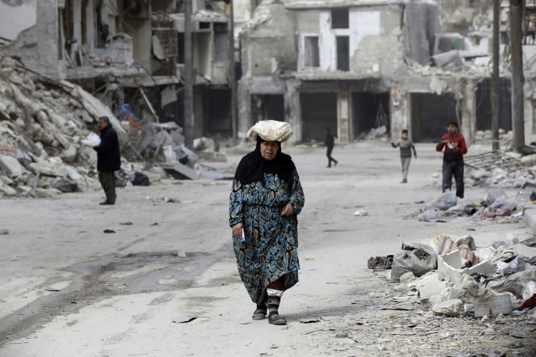 A woman walks up a street lined with heavily-damaged buildings in former rebel-held district of Shaar that Syrian government forces recaptured in December, in picture taken on March 9