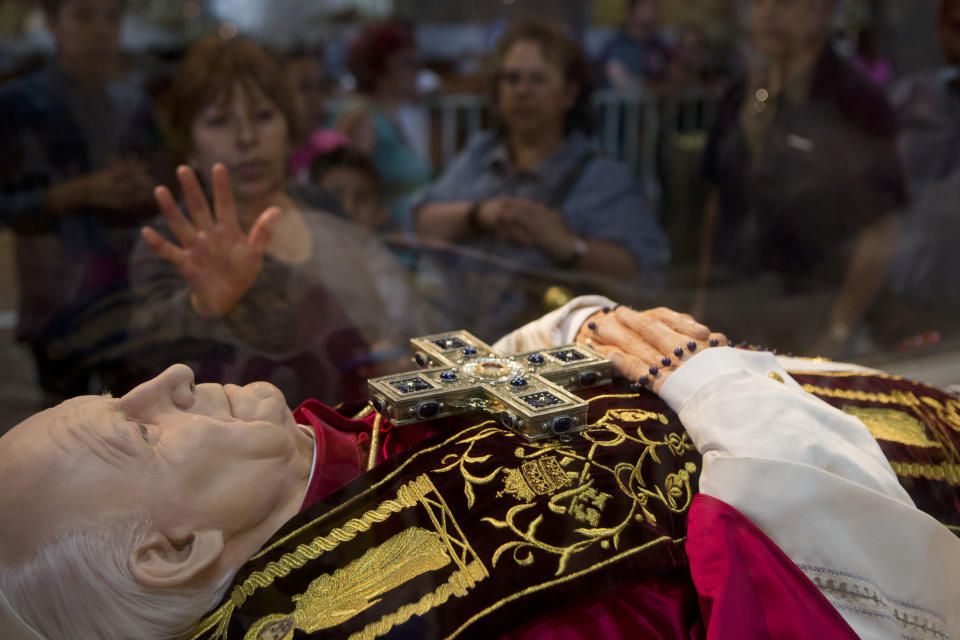 Una mujer toca la caja de cristal que protege una efigie del papa Juan Pablo II en la Basílica de Guadalupe en la Ciudad de México, el viernes 25 de abril de 2014. La canonización del pontífice atrae especial atención en Latinoamérica, al traer a la memoria cálidos recuerdos sobre sus frecuentes visitas a la región y avivar el debate sobre su manejo en torno a los escándalos de abuso sexual. (Foto AP/Rebecca Blackwell)