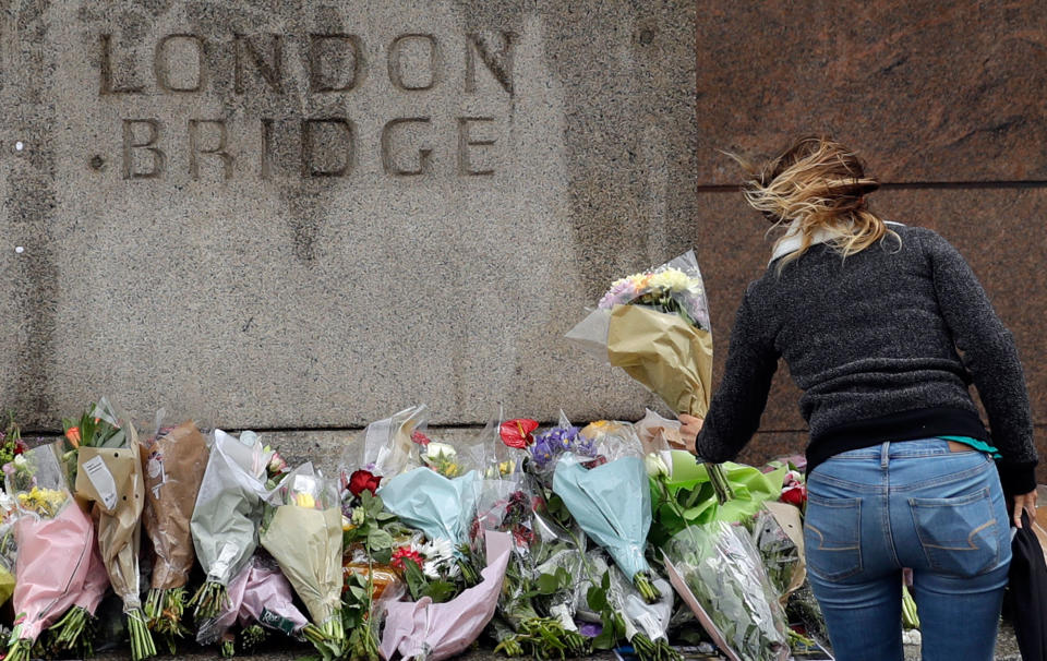 A woman places flowers on a memorial