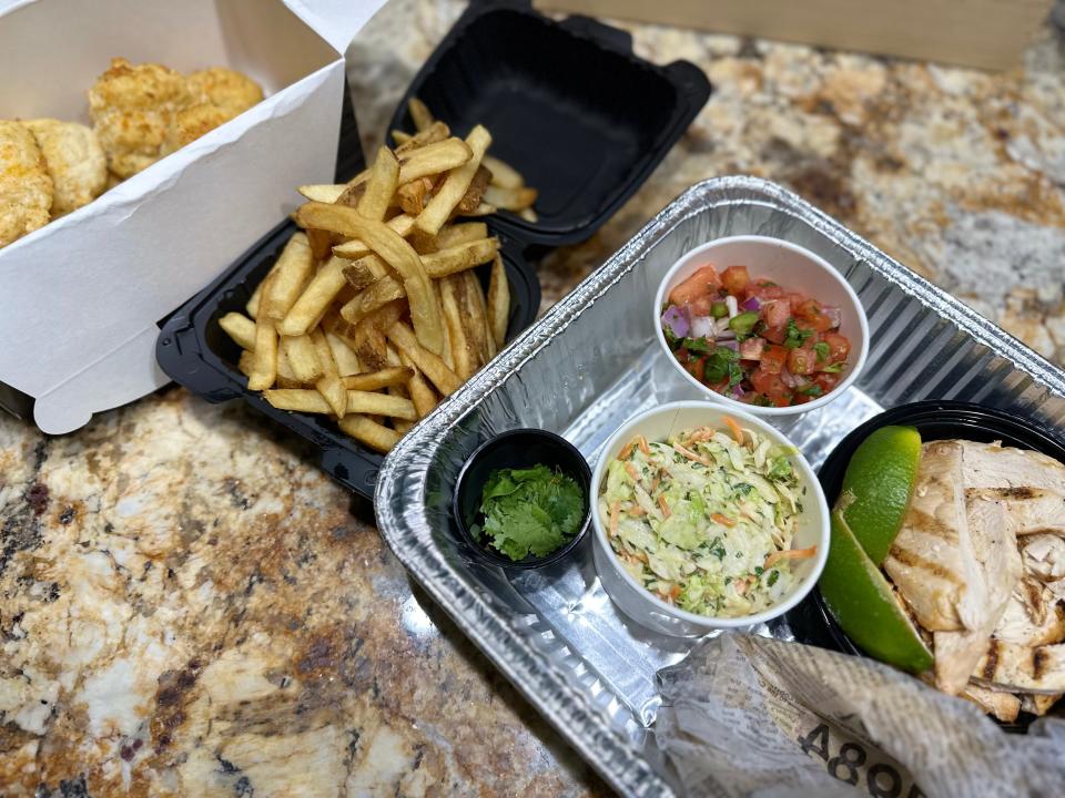 Foil pan of taco ingredients next to takeout container of fries and cheddar biscuits from Red Lobster