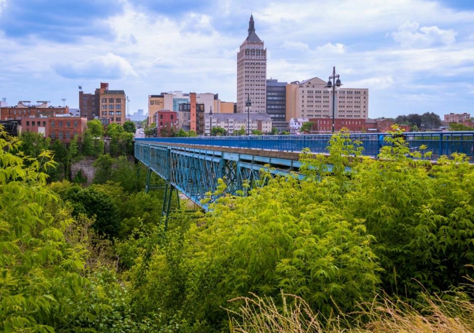 City skyline with blue steel bridge among trees.