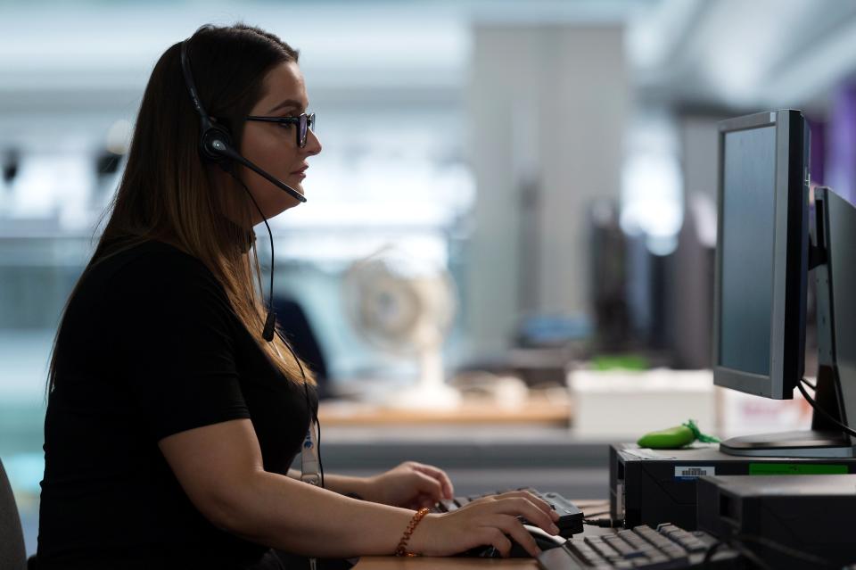 A woman wearing a headset and looking at a computer at a call center