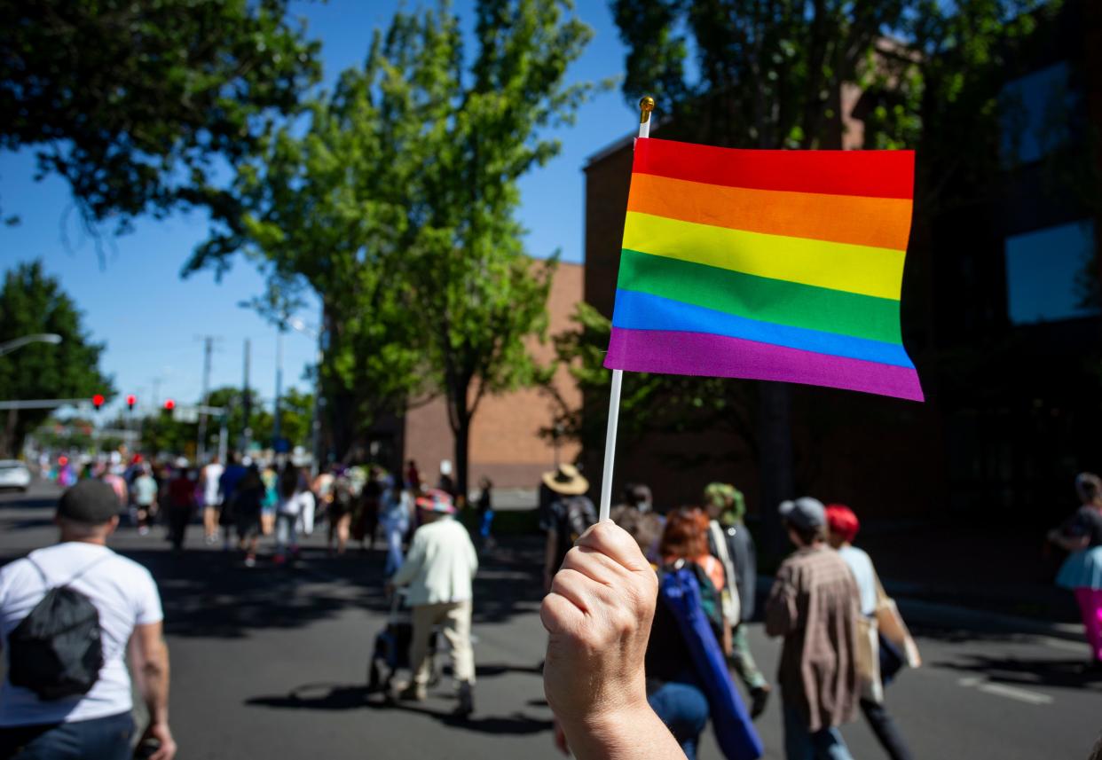 A marcher waves a Pride flag while walking to Eugene’s 2022 Pride in the Park event.