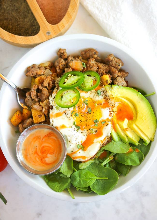 A breakfast bowl with potato, egg, spinach, and avocado.