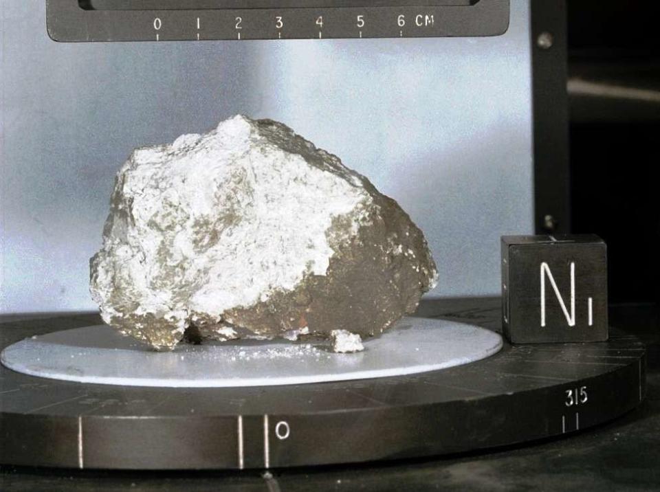 La pierre de la Gen&#xe8;se, &#xe9;chantillon d&#39;anorthosite lunaire. Il s&#39;agit d&#39;une roche quasi exclusivement constitu&#xe9;e de feldspath plagioclase. Juste apr&#xe8;s son retour sur Terre (en 1971), cette roche a &#xe9;t&#xe9; dat&#xe9;e &#xe0; -4,5 Ga, ce qui en faisait l&#39;&#xe9;chantillon le plus vieux du Syst&#xe8;me solaire (hors m&#xe9;t&#xe9;orites, et c&#39;est pour cela que cet &#xe9;chantillon a &#xe9;t&#xe9; nomm&#xe9; pierre de la Gen&#xe8;se), et donnait &#xe0; la Lune un &#xe2;ge sup&#xe9;rieur ou &#xe9;gal &#xe0; ce chiffre. Ce serait un fragment de la cro&#xfb;te lunaire profonde, fragment contemporain (&#xe0; 1 million d&#39;ann&#xe9;es pr&#xe8;s) de la formation de la Lune, et remont&#xe9; &#xe0; la surface il y a 3,9 Ga par l&#39;impact d&#39;Imbrium. De nouvelles datations proposent un &#xe2;ge plus r&#xe9;cent (4,4 Ga, voire moins) &#xe0; certains &#xe9;chantillons d&#39;anorthosite, ce qui remet en question cette interpr&#xe9;tation classique, ou qui rajeunit l&#39;&#xe2;ge de la Lune et donc de l&#39;impact de Th&#xe9;ia. &#xa9; 1971 Nasa, mission Apollo 15,...