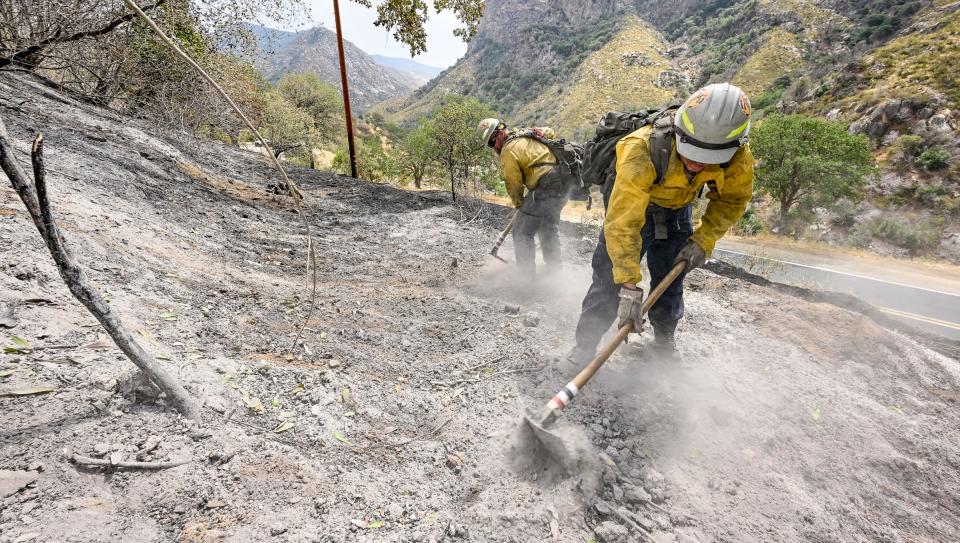 Kyler Chico, right, and Charles Dabney, Jr. turn over ash and embers Wednesday, August 17 from the Wishon fire near The Stairs picnic area along Highway 190