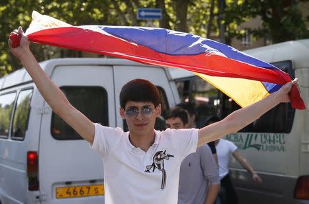 An opposition supporter holds an Armenian flag during a rally to commemorate the 103rd anniversary of mass killing of Armenians by Ottoman Turks, in central Yerevan, Armenia April 24, 2018. REUTERS/Gleb Garanich