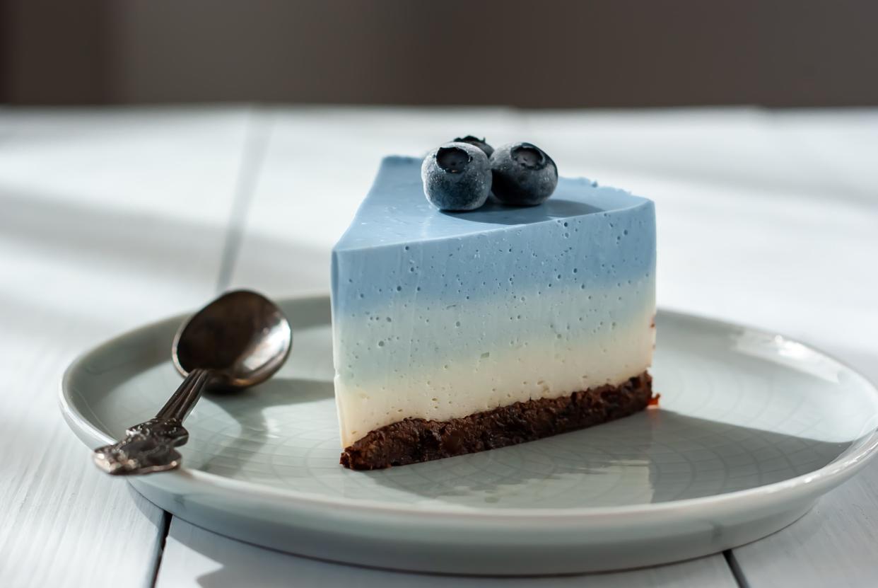 Homemade blue butterfly pea cheesecake with fresh berries on a light background