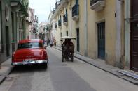 FILE PHOTO: A bicycle taxi passes by a parked vintage American car in Havana