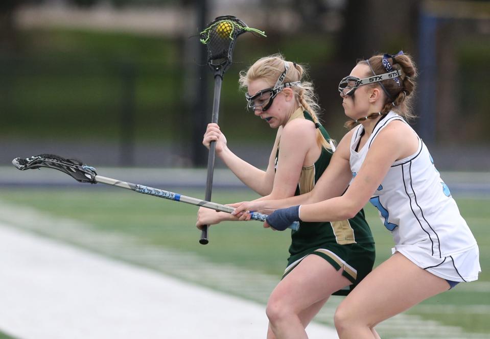 Kaidyn Watson (left) of GlenOak brings the ball upfield while being guarded by Hallie Schillig (right) of Louisville during Wednesday's girls lacrosse game.