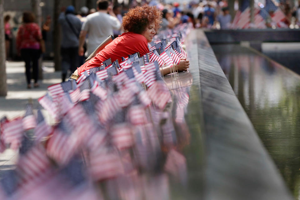 <p>A woman pauses among American flags that were inserted in each of the 2.983 names on the borders of the reflecting pools of the 9/11 Memorial, in New York, Tuesday, July 4, 2017. (Photo: Richard Drew/AP) </p>