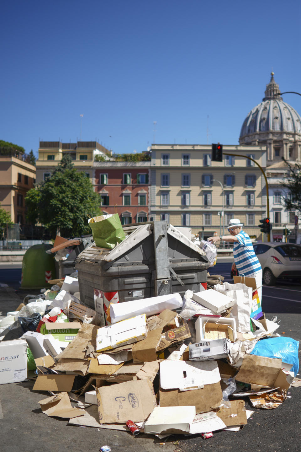In this photo taken on Monday, June 24, 2019, a man stands by uncollected garbage in Rome. Doctors in Rome are warning of possible health hazards caused by overflowing trash bins in the city streets, as the Italian capital struggles with a renewed garbage emergency aggravated by the summer heat. (AP Photo/Andrew Medichini)